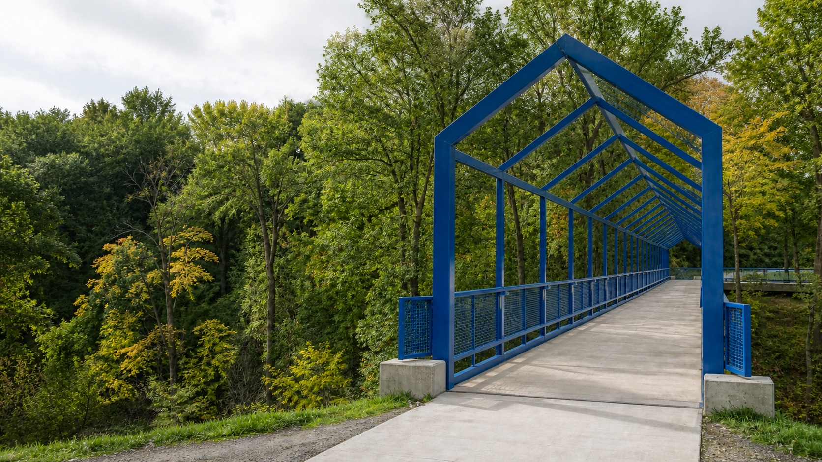 A blue enclosed pedestrian bridge crossing a wooded ravine, inspired by GVSU's Little Mac Bridge